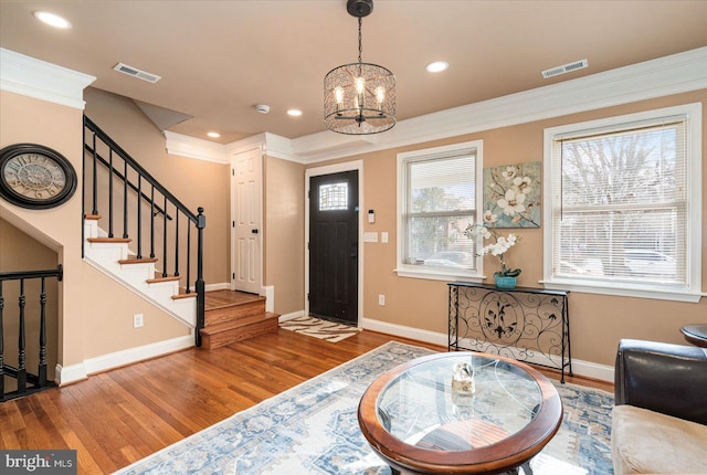 entryway featuring a notable chandelier, hardwood / wood-style flooring, and ornamental molding