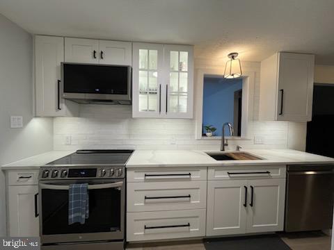 kitchen with sink, stainless steel appliances, and white cabinetry