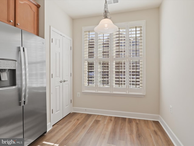 kitchen with stainless steel refrigerator with ice dispenser, light hardwood / wood-style floors, and decorative light fixtures