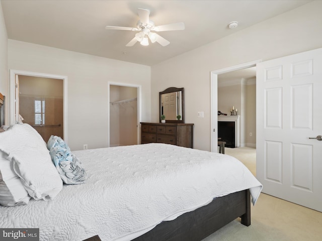 bedroom with ceiling fan, light colored carpet, a closet, and a spacious closet