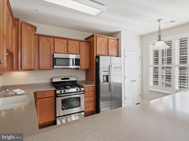 kitchen with decorative light fixtures, sink, and appliances with stainless steel finishes