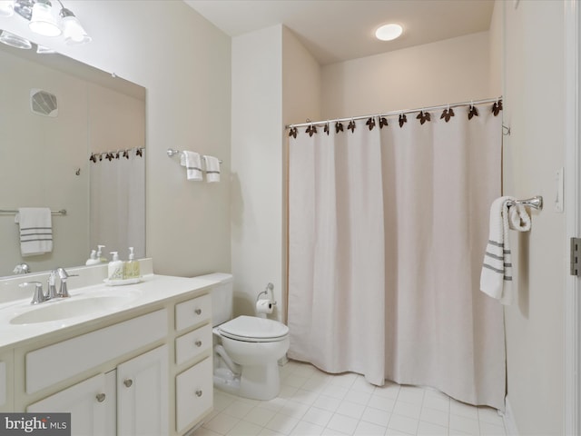 bathroom with toilet, vanity, and tile patterned flooring