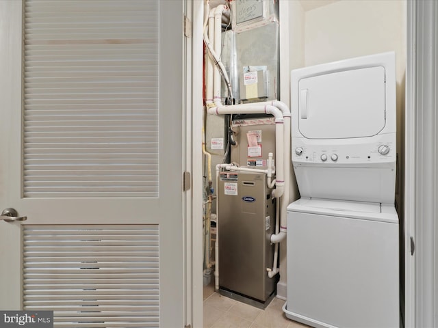 washroom with heating unit and stacked washer and clothes dryer