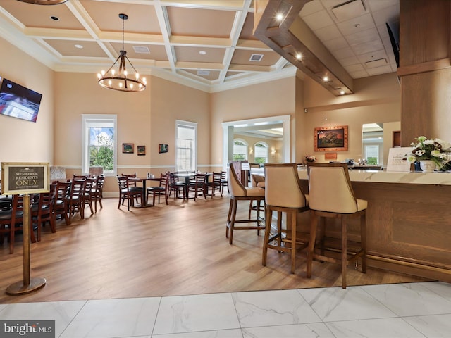 dining room featuring a high ceiling, light wood-type flooring, an inviting chandelier, and coffered ceiling