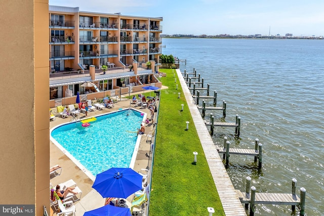 view of pool featuring a water view, a lawn, a patio area, and a dock