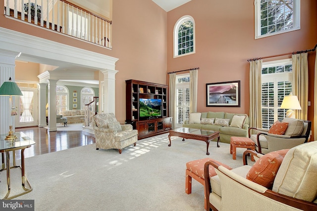 carpeted living room with a towering ceiling and decorative columns