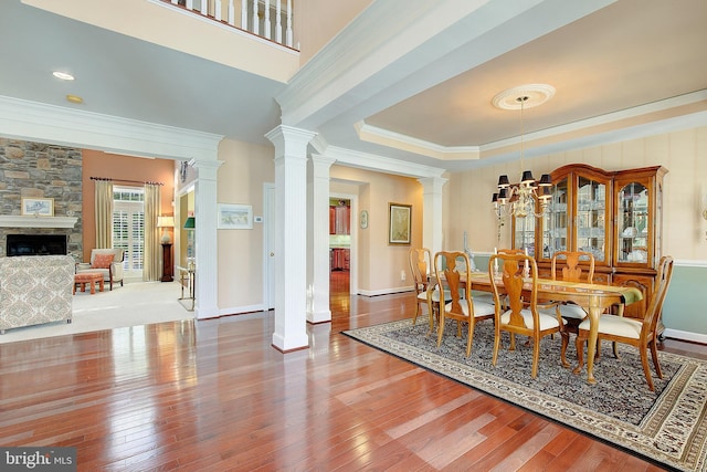 dining room featuring crown molding, wood-type flooring, and decorative columns