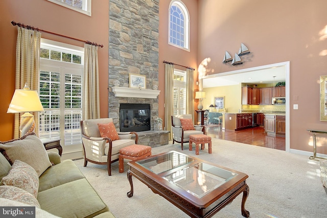 carpeted living room with a towering ceiling and a stone fireplace