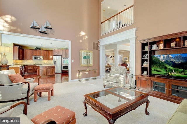 living room with ornate columns, a high ceiling, sink, and light colored carpet