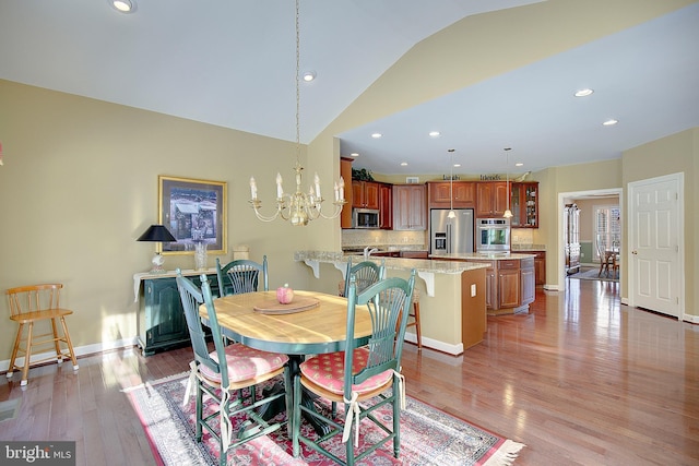 dining area featuring lofted ceiling, a notable chandelier, and light hardwood / wood-style floors