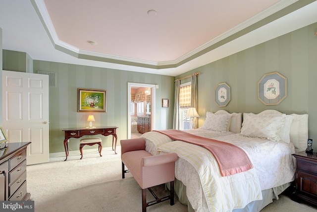 bedroom with a raised ceiling, ornamental molding, light carpet, and ensuite bathroom