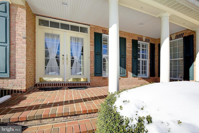 snow covered property entrance featuring french doors