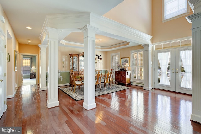 entrance foyer with ornate columns, plenty of natural light, and hardwood / wood-style floors