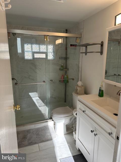 bathroom with toilet, tile patterned floors, an enclosed shower, and vanity