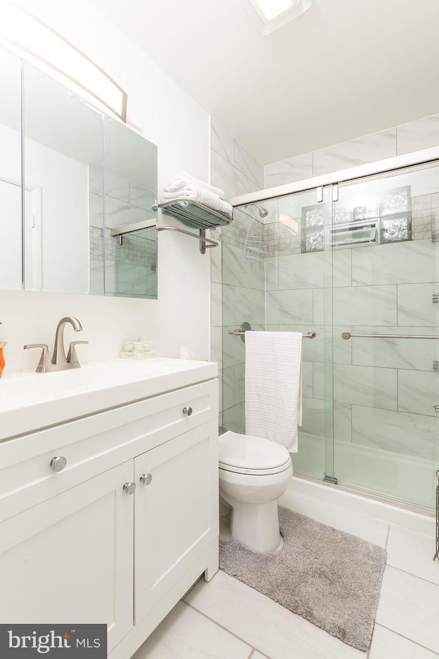 bathroom with a shower with shower door, vanity, tile patterned floors, and toilet