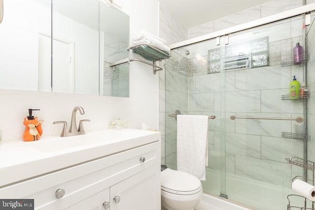 bathroom featuring toilet, a shower with shower door, and vanity