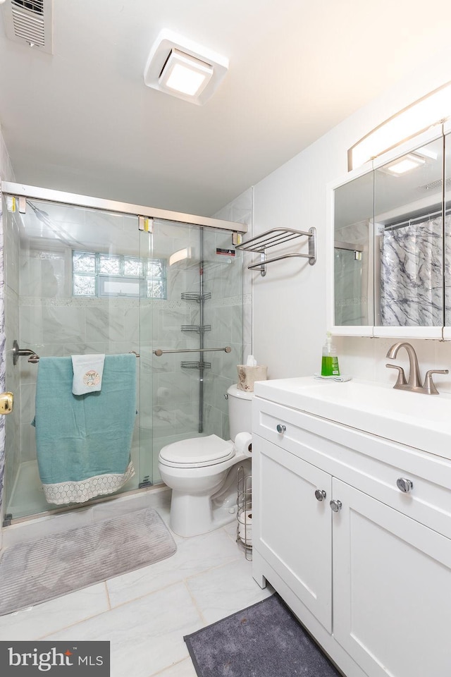 bathroom featuring toilet, vanity, and a shower with shower door