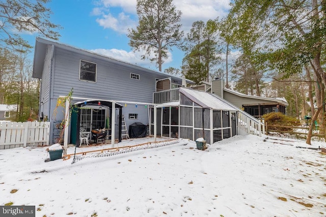 snow covered back of property with a sunroom