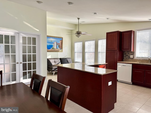 kitchen featuring light tile patterned floors, dishwasher, decorative backsplash, vaulted ceiling, and french doors