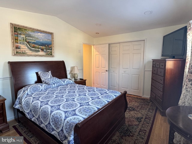 bedroom with dark wood-type flooring, vaulted ceiling, and a closet