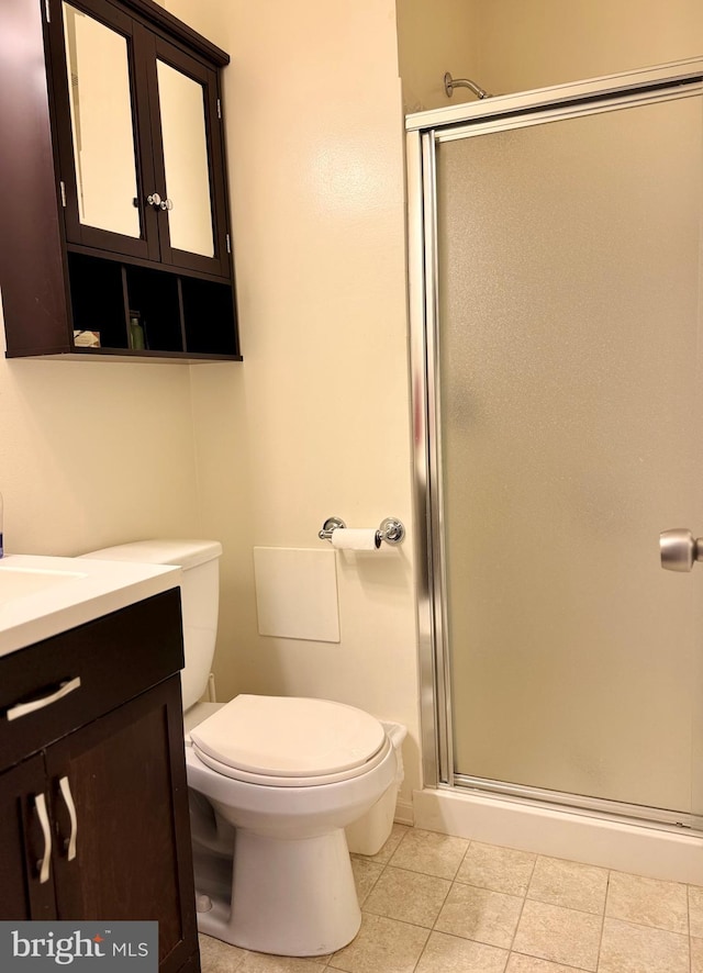 bathroom featuring vanity, tile patterned floors, toilet, and walk in shower