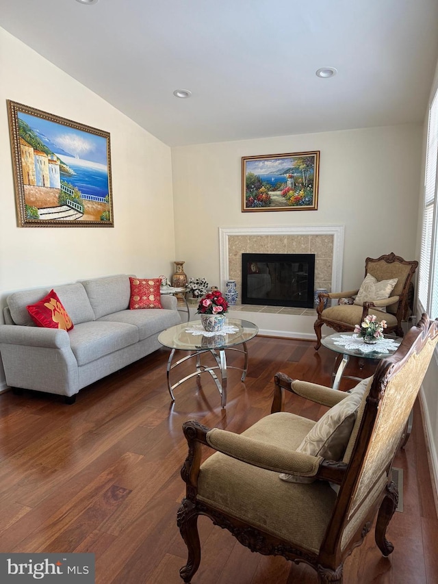 living room with a tiled fireplace, lofted ceiling, and dark hardwood / wood-style floors