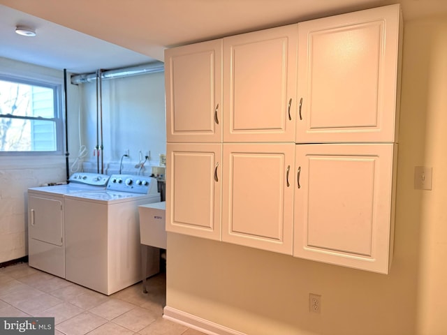 washroom featuring cabinets, washing machine and dryer, and light tile patterned floors