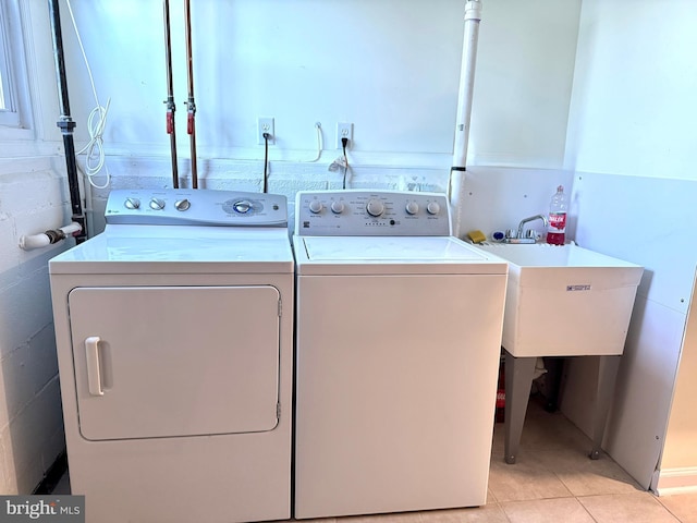 washroom with washing machine and dryer, sink, and light tile patterned floors