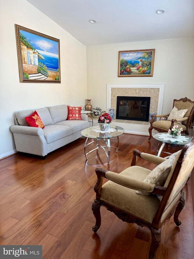 living room with a tiled fireplace, hardwood / wood-style floors, and lofted ceiling