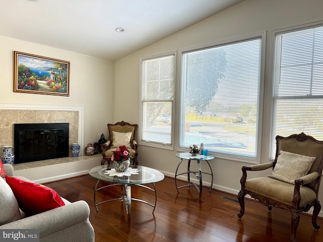 living room featuring a tiled fireplace, hardwood / wood-style floors, and lofted ceiling