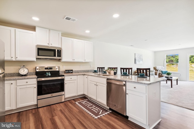 kitchen with white cabinets, appliances with stainless steel finishes, and kitchen peninsula