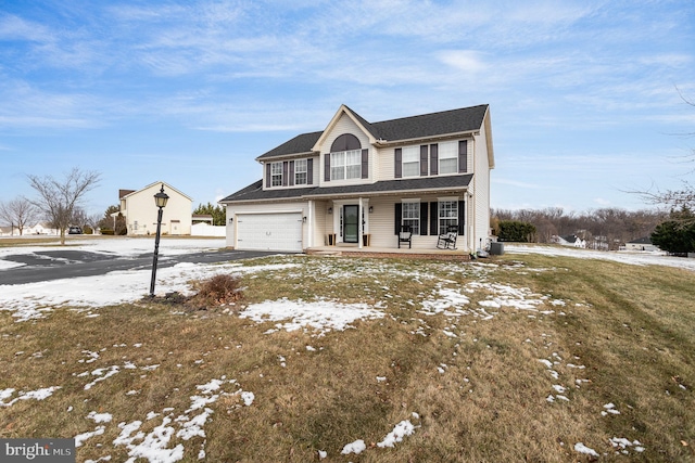 view of front of home with a yard, covered porch, and a garage