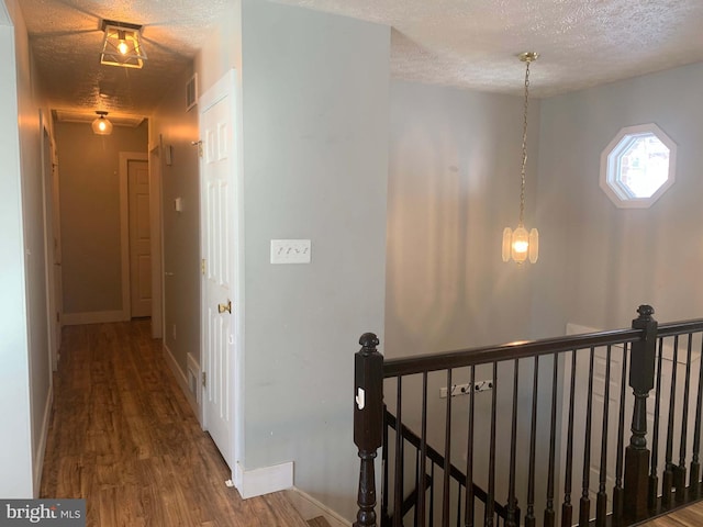 corridor with a textured ceiling and hardwood / wood-style floors