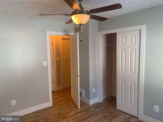 unfurnished bedroom featuring a closet, dark hardwood / wood-style flooring, a textured ceiling, and ceiling fan