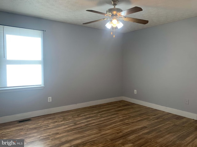 unfurnished room featuring dark hardwood / wood-style flooring, a textured ceiling, and a wealth of natural light