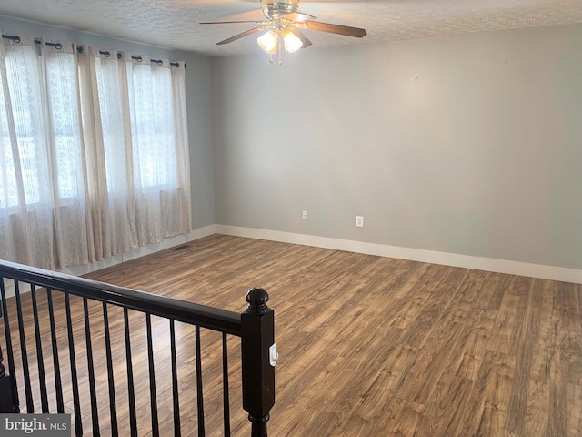 empty room featuring a textured ceiling, ceiling fan, and wood-type flooring