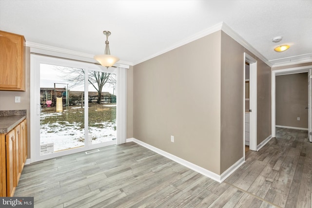 unfurnished dining area with a textured ceiling, crown molding, and light hardwood / wood-style flooring