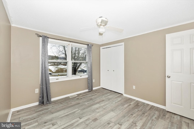 unfurnished bedroom featuring ceiling fan, a closet, ornamental molding, and light hardwood / wood-style flooring