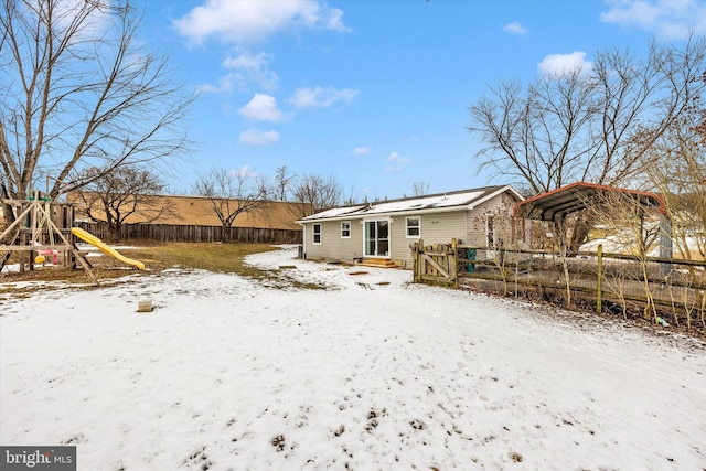 snow covered house featuring a carport and a playground