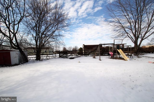 yard layered in snow featuring a playground