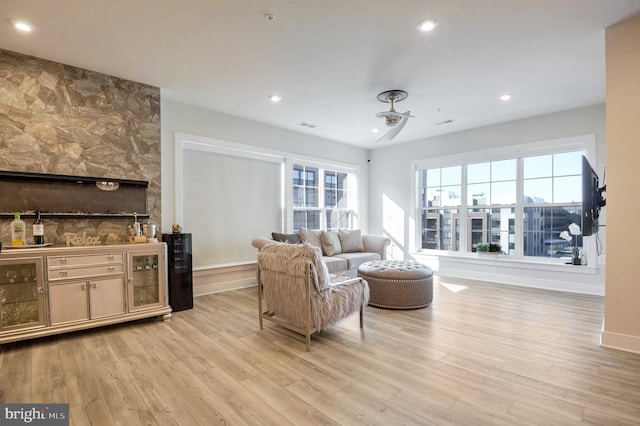 living room with bar area, ceiling fan, and light hardwood / wood-style flooring