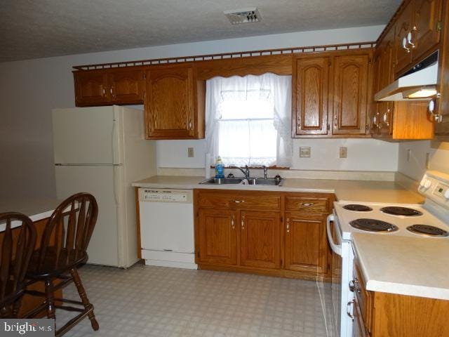 kitchen with a textured ceiling, white appliances, and sink