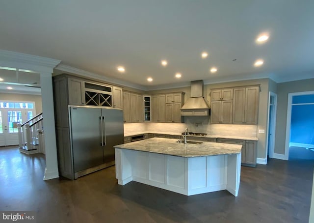 kitchen featuring light stone counters, backsplash, a kitchen island with sink, custom range hood, and appliances with stainless steel finishes