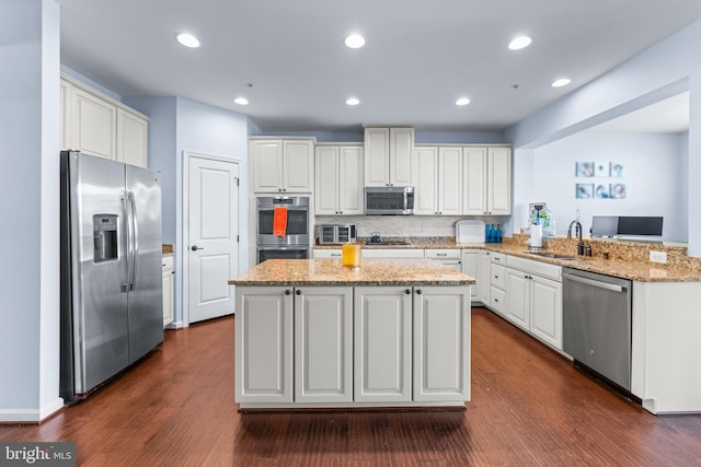 kitchen featuring appliances with stainless steel finishes, kitchen peninsula, dark wood-type flooring, sink, and white cabinetry