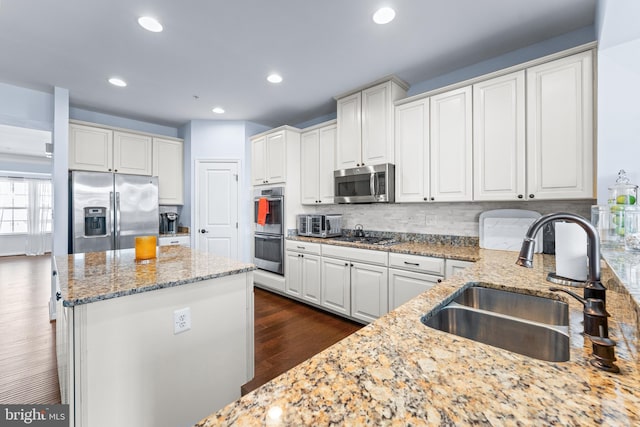 kitchen with light stone counters, stainless steel appliances, white cabinetry, and sink