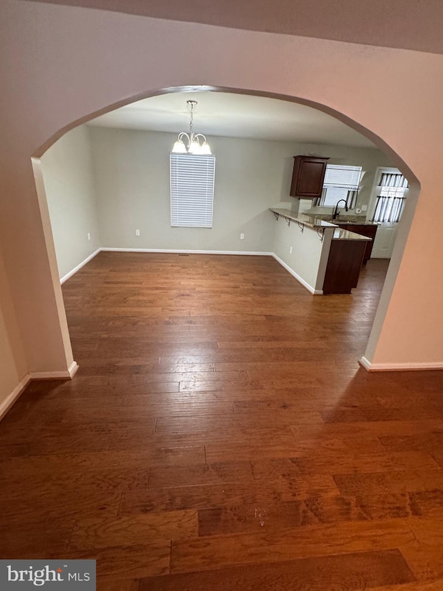 unfurnished dining area with sink, dark hardwood / wood-style flooring, and a notable chandelier