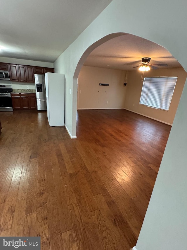 unfurnished living room featuring dark hardwood / wood-style floors and ceiling fan