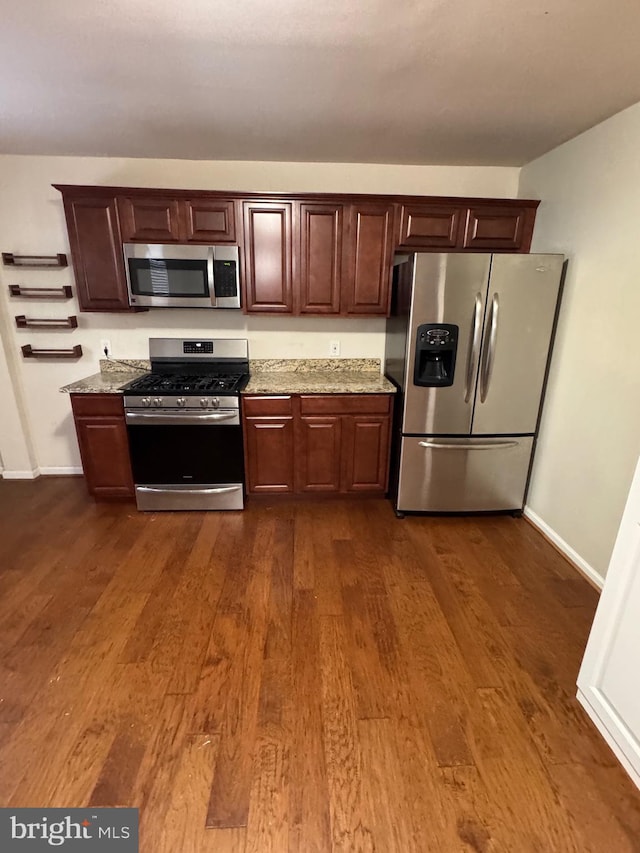 kitchen featuring light stone countertops, stainless steel appliances, and dark wood-type flooring