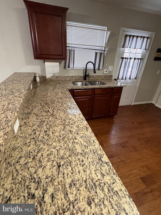 kitchen featuring dark hardwood / wood-style flooring, light stone counters, and sink