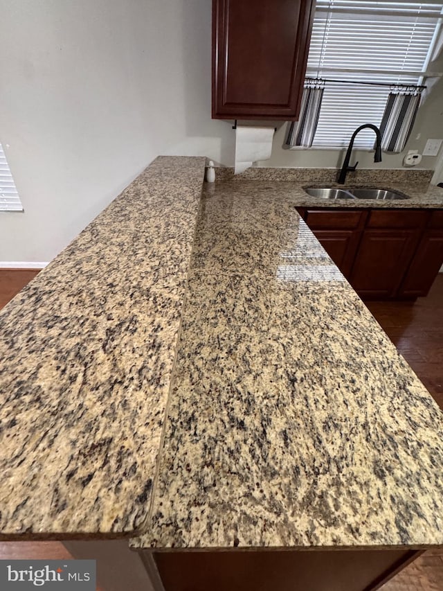 interior details featuring stone counters, dark hardwood / wood-style flooring, kitchen peninsula, and sink